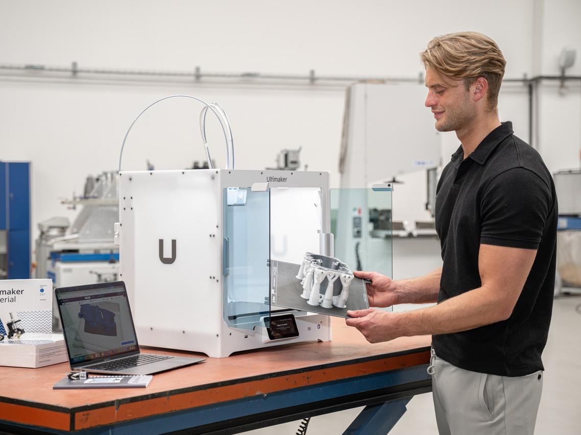 Der Ultimaker S6 in einer Hallo, wo ein Mann ein gedrucktes Teil aus dem 3D Drucker nimmt Der Ultimaker S6 in einer Hallo, wo ein Mann ein gedrucktes Teil aus dem 3D Drucker nimmt