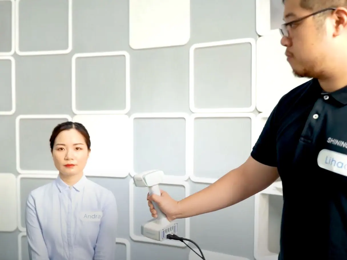 Eine Frau wird in einer Lichtkammer mit einem Hand 3D Scanner eingescannt