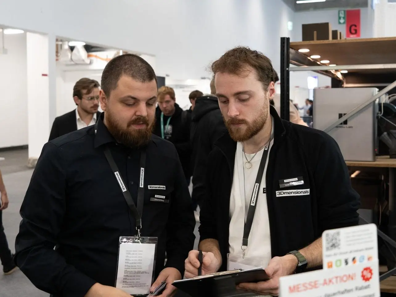 2 Angestellte von 3Dmensionals gucken auf ein Klemmbrett