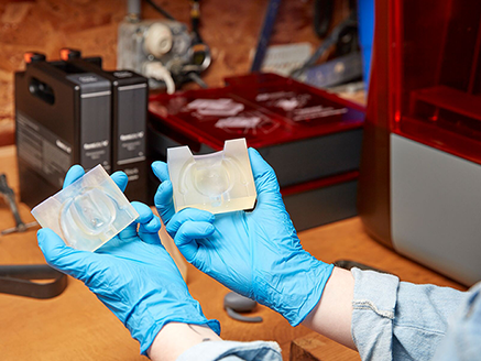 zwei hände mit gummihandschuhen zeigen 2 3d gedruckte teile