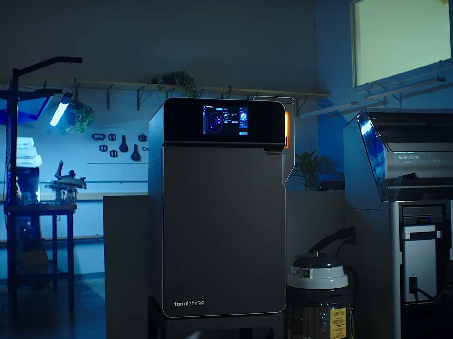 im vordergrund, blau beleuchtet steht ein sls drucker von formlabs, daneben steht der sift